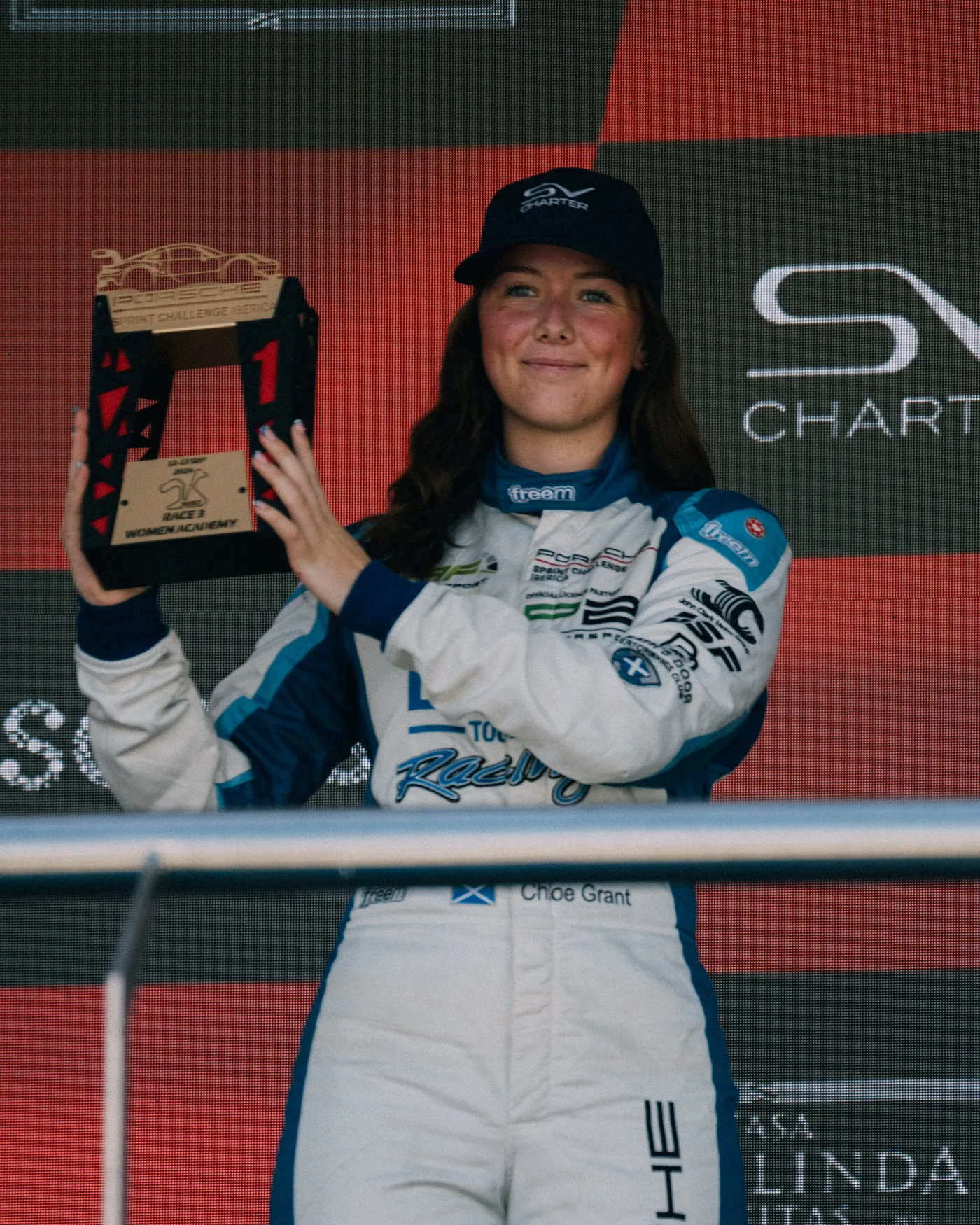 Chloe Grant holding her trophy up on the podium
